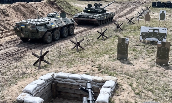 A military training range equipped with a dugout, anti-tank hedgehogs, and heavy armored vehicles (APCs and tanks) for training in engaging enemy equipment and breaching fortifications