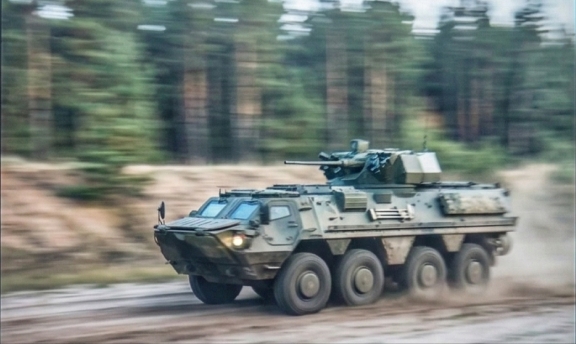 An armored personnel carrier moving at high speed during military exercises at a training range